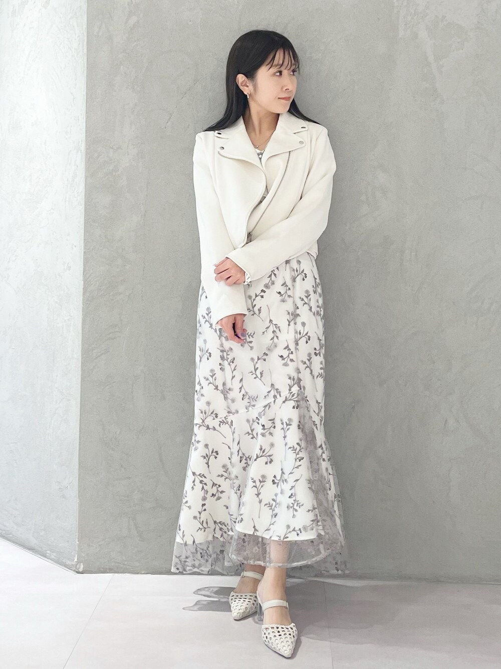 グレー系のワンピース、ホワイト系のパンプス、ホワイト系のライダースジャケットを着用したレディースの春コーディネートの1枚目の写真