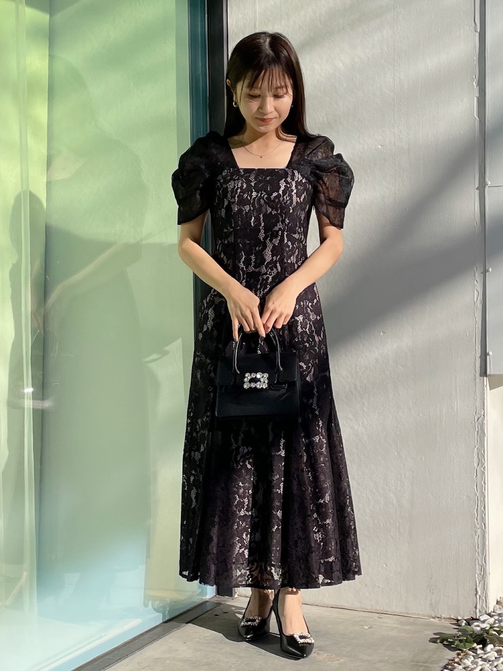 ブラック系のパンプス、ブラック系のショルダーバッグ、ブラック系のドレスを着用したレディースの春コーディネートの1枚目の写真