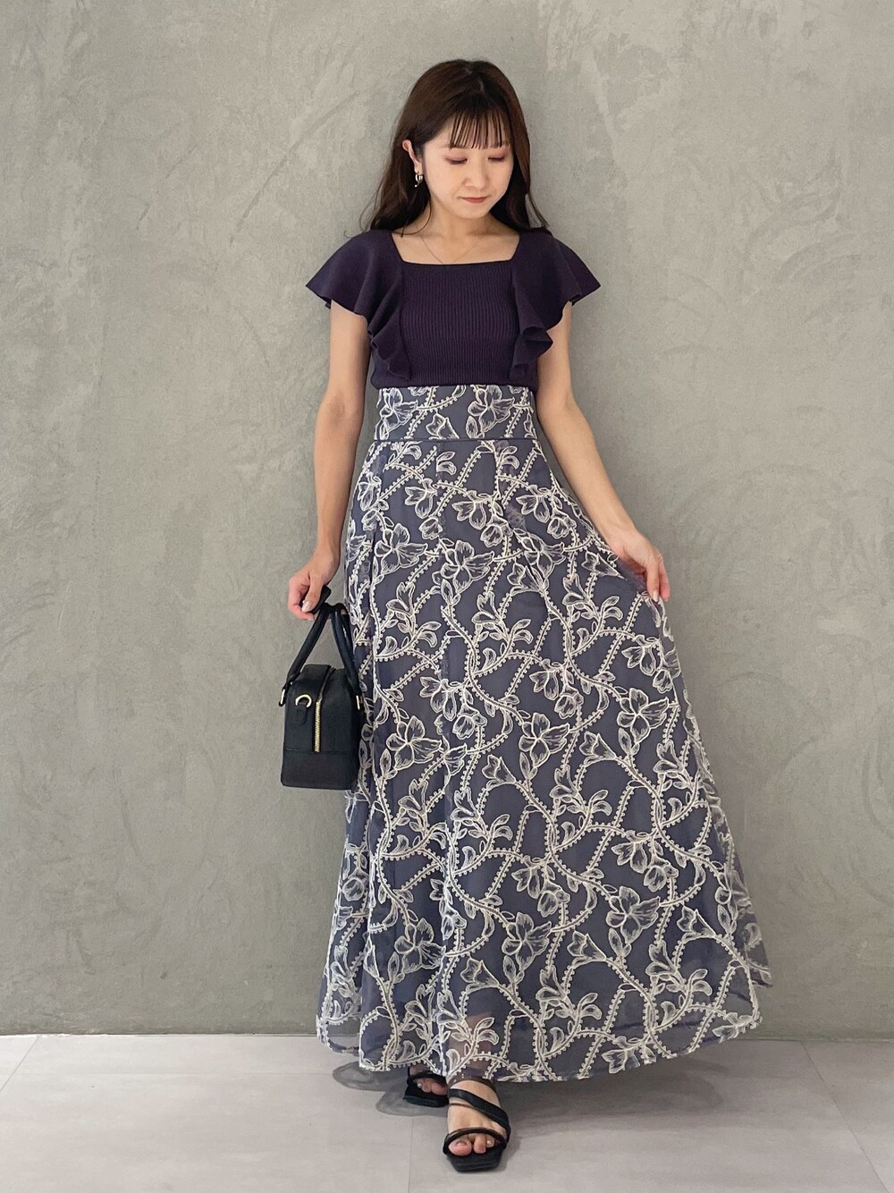 グレー系のスカート、グレー系のニット/セーター、ブラック系のサンダルを着用したレディースの夏コーディネートの1枚目の写真