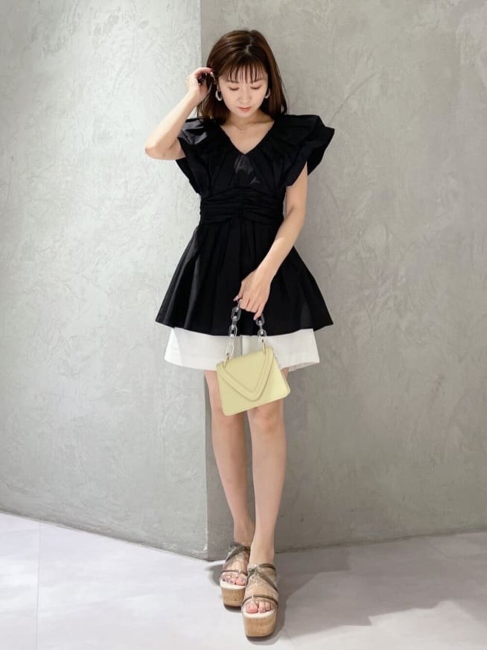 イエロー系のショルダーバッグ、グリーン系のサンダル、ブラック系のシャツ/ブラウスを着用したレディースの春コーディネートの1枚目の写真