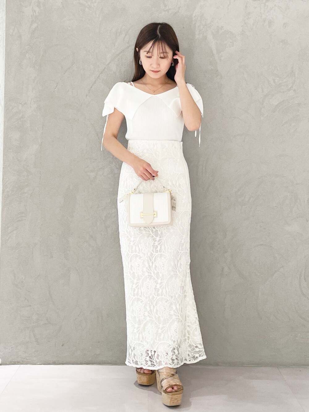 ホワイト系のハンドバッグ、ホワイト系のニット/セーター、ホワイト系のスカートを着用したレディースの春コーディネートの1枚目の写真