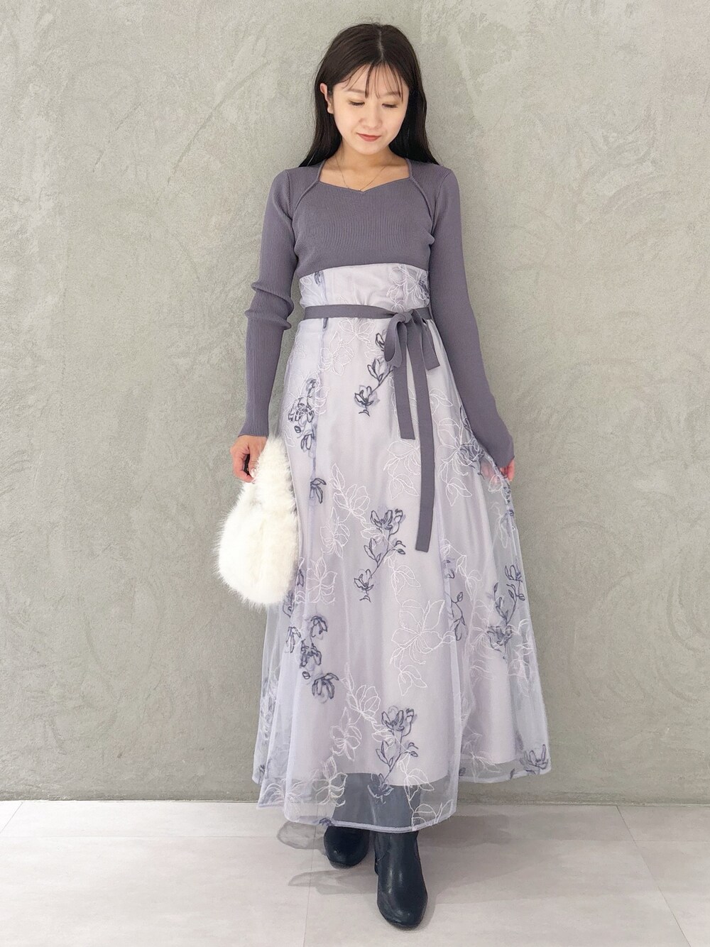 パープル系のワンピース、ブラック系のブーツ、ホワイト系のハンドバッグを着用したレディースの秋コーディネートの1枚目の写真