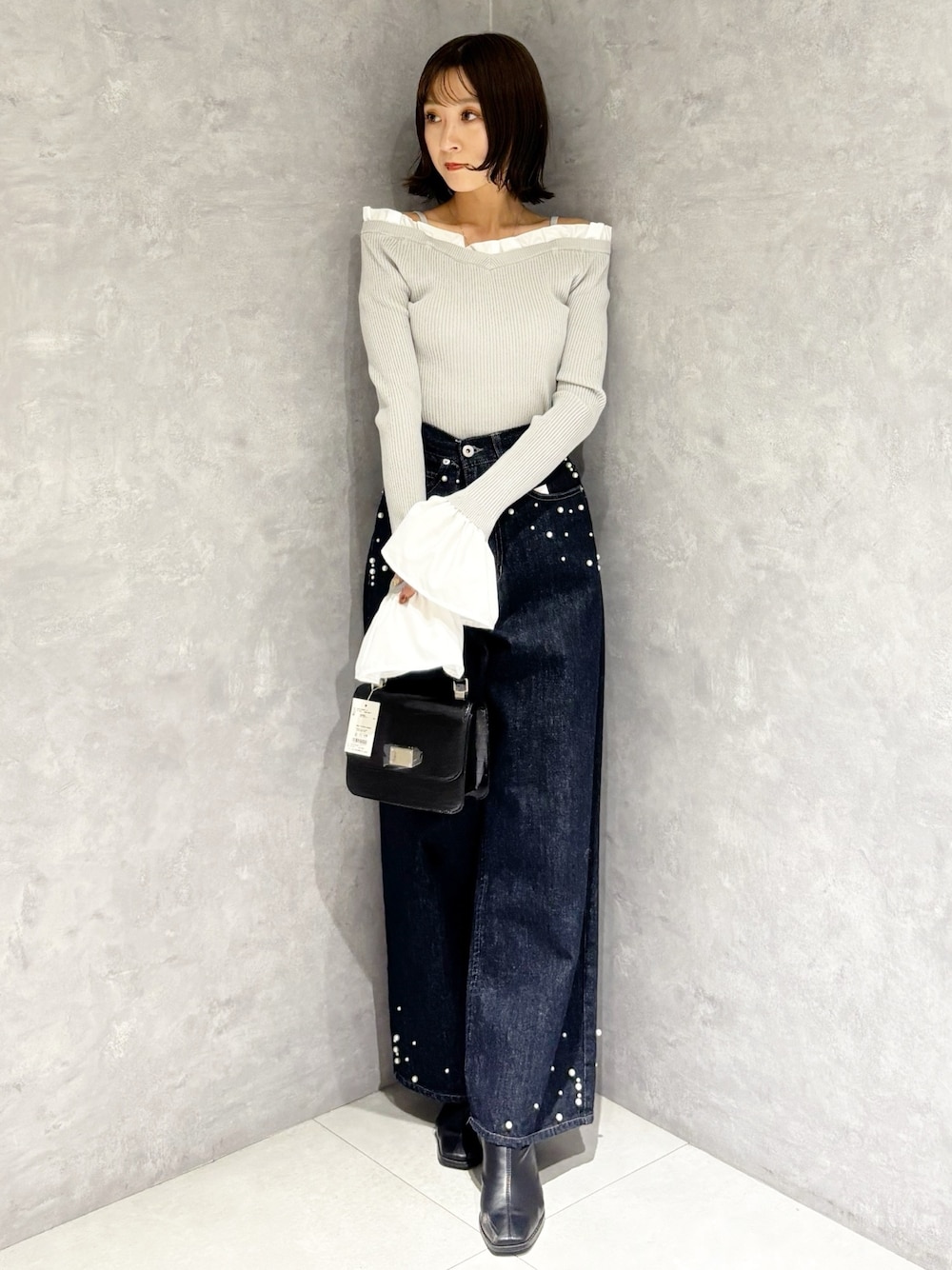 グレー系のニット/セーター、ブルー系のデニムパンツ、ブラック系のブーツを着用したレディースの秋コーディネートの1枚目の写真