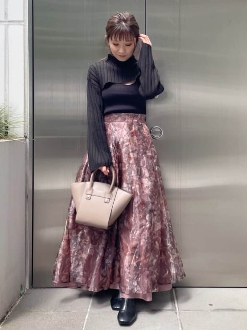 ブラウン系のスカート、ブラック系のニット/セーター、ブラック系のブーツを着用したレディースの秋コーディネートの1枚目の写真