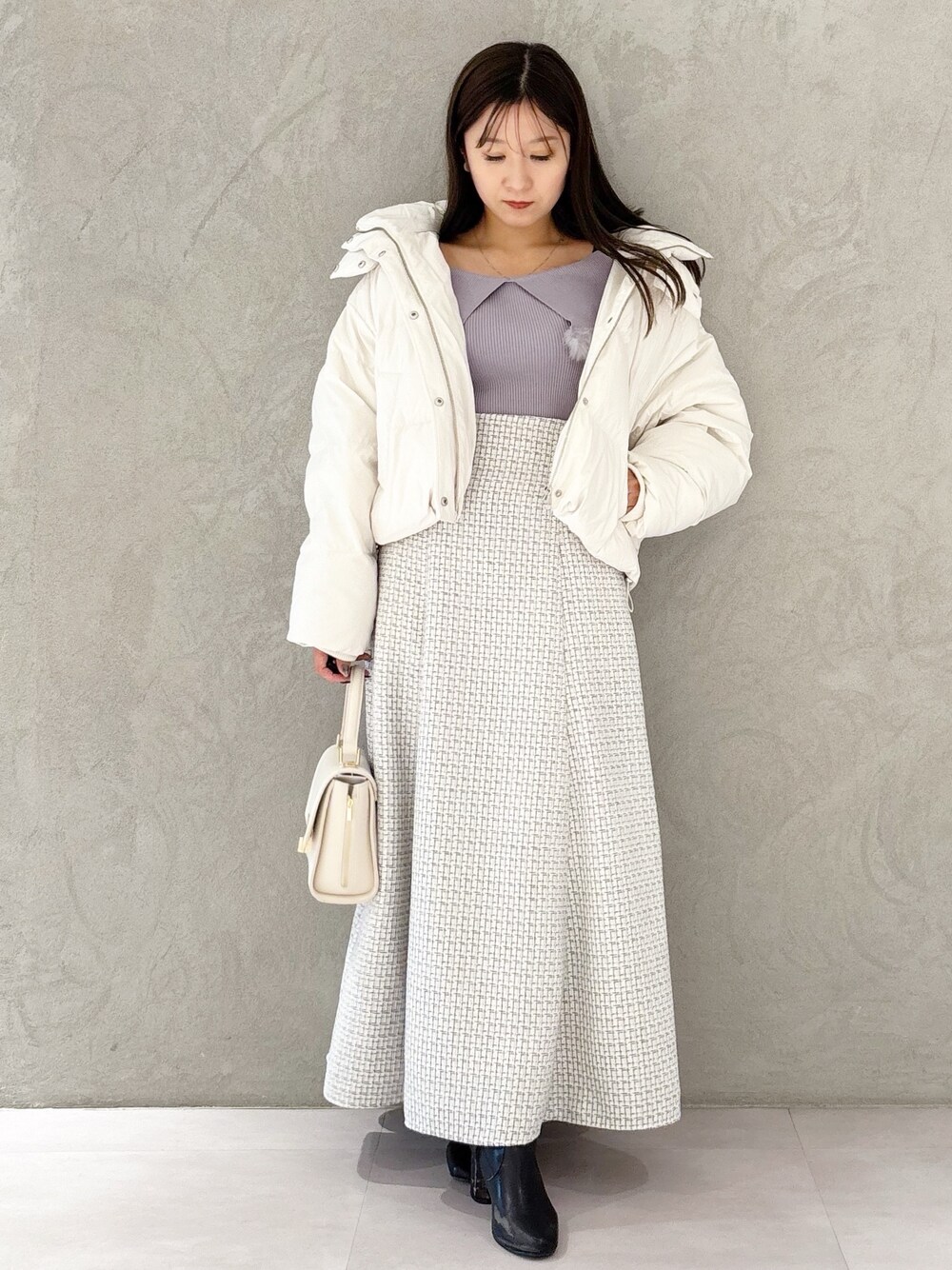 ホワイト系のスカート、ブラック系のブーツ、ホワイト系のハンドバッグを着用したレディースの冬コーディネートの1枚目の写真