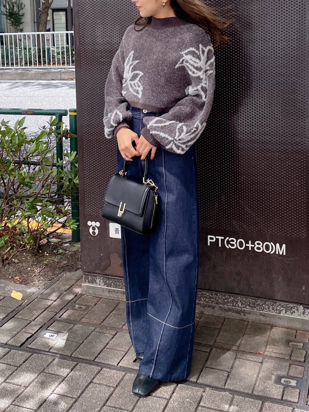 ブラック系のショルダーバッグ、グレー系のニット/セーター、ブルー系のデニムパンツを着用したレディースの秋コーディネートの1枚目の写真