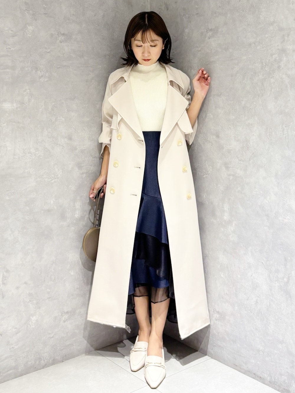 ブルー系のスカート、ホワイト系のニット/セーター、ホワイト系のパンプスを着用したレディースの春コーディネートの1枚目の写真