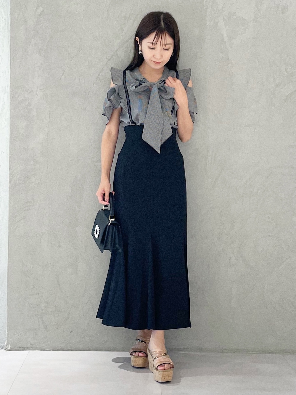 ブラック系のスカート、ブラウン系のサンダル、ブラック系のショルダーバッグを着用したレディースの夏コーディネートの1枚目の写真