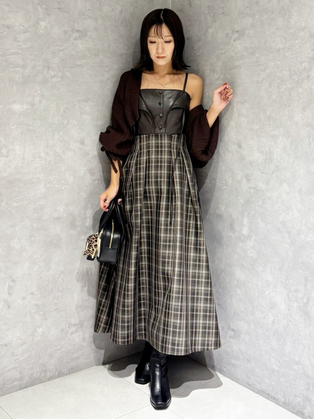ブラウン系のワンピース、ブラック系のブーツ、ブラック系のハンドバッグを着用したレディースの秋コーディネートの1枚目の写真