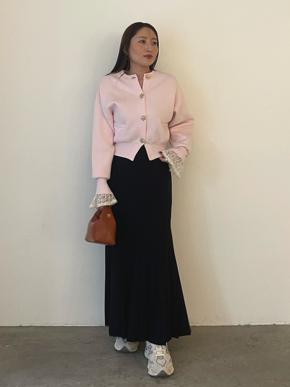 ピンク系のカーディガン/ボレロ、ホワイト系のシャツ/ブラウス、ブラウン系のハンドバッグを着用したレディースの冬コーディネートの1枚目の写真