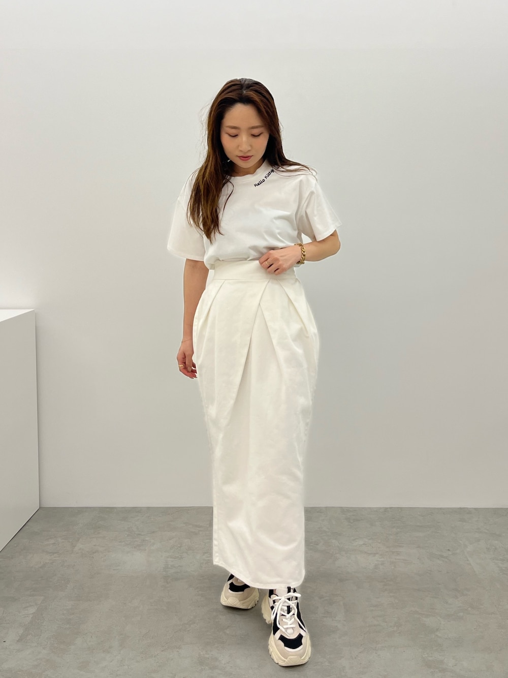 ブラック系のスニーカー、ホワイト系のデニムスカート、ホワイト系のTシャツ/カットソーを着用したレディースの春コーディネートの1枚目の写真