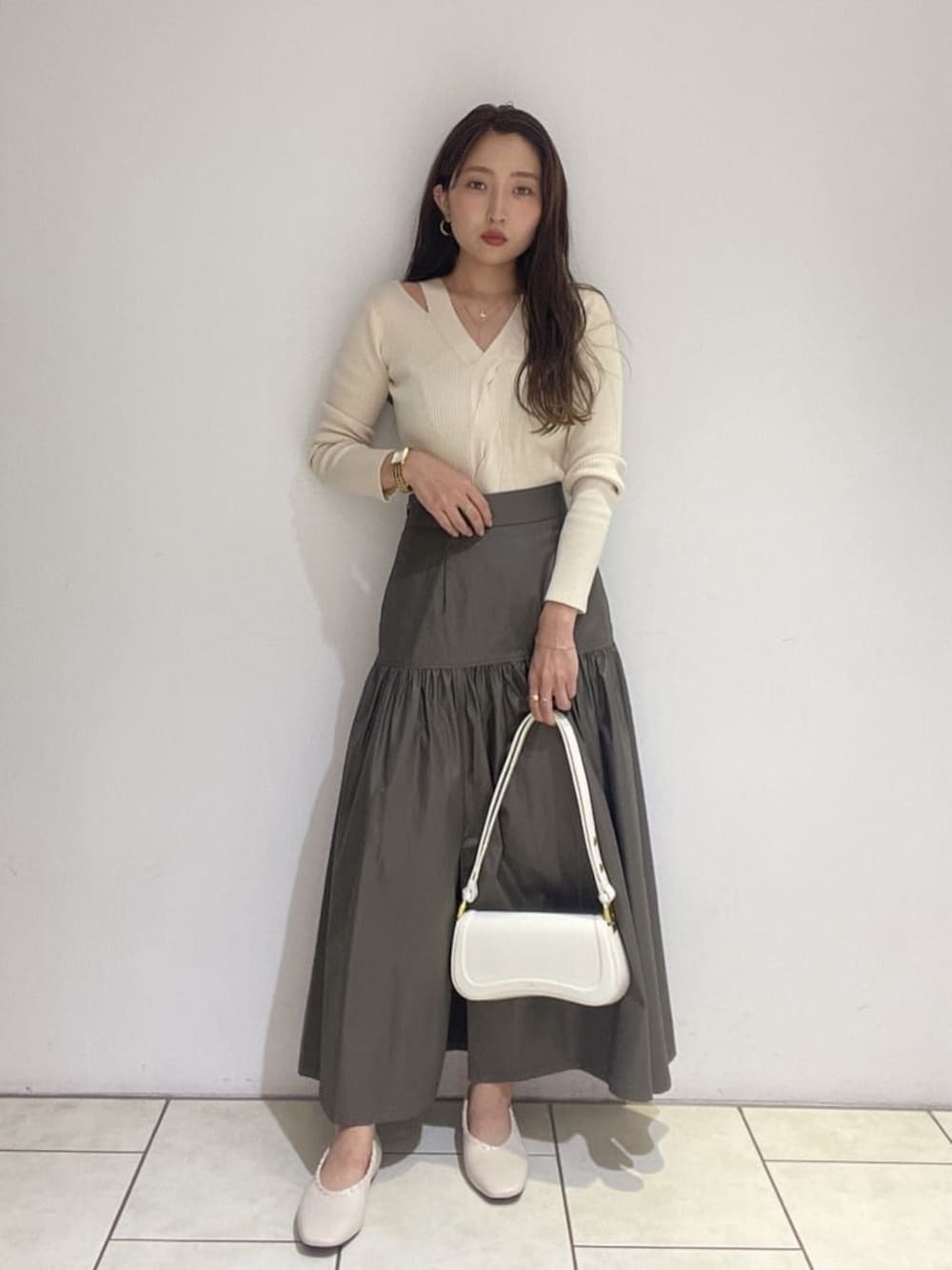 ベージュ系のスカート、ホワイト系のパンプス、ホワイト系のニット/セーターを着用したレディースの夏コーディネートの1枚目の写真