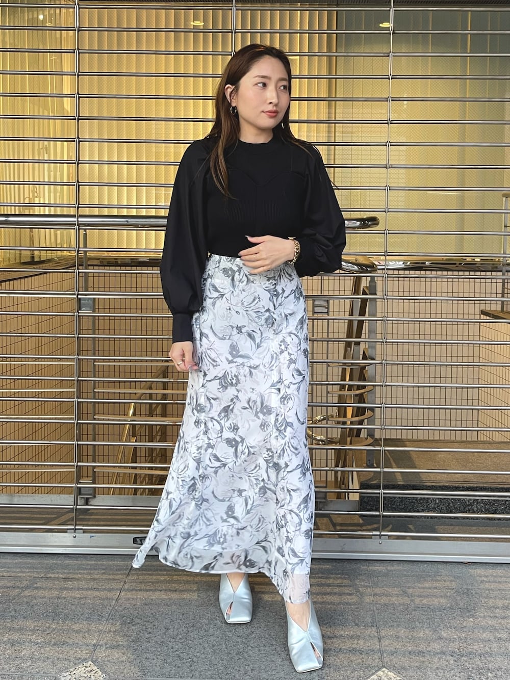 グレー系のスカート、シルバー系のパンプス、ブラック系のニット/セーターを着用したレディースの冬コーディネートの1枚目の写真