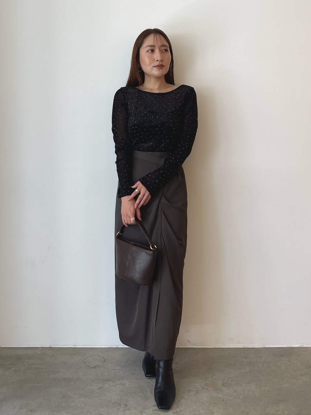 ブラック系のTシャツ/カットソー、ブラウン系のハンドバッグ、ブラウン系のスカートを着用したレディースの秋コーディネートの1枚目の写真