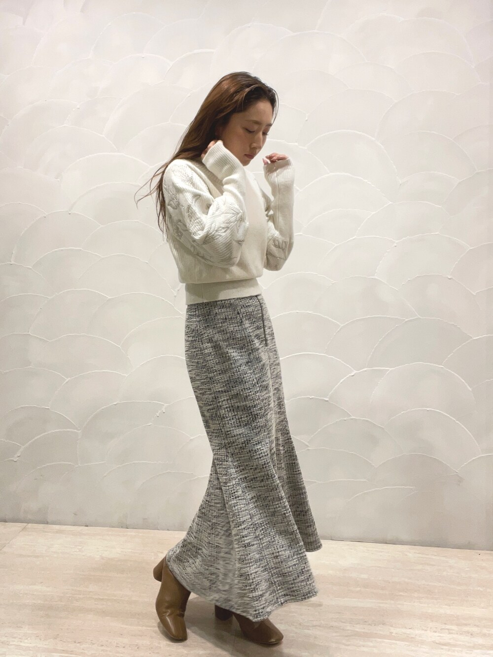 ホワイト系のニット/セーター、ブラック系のスカート、ベージュ系のブーツを着用したレディースの秋コーディネートの1枚目の写真