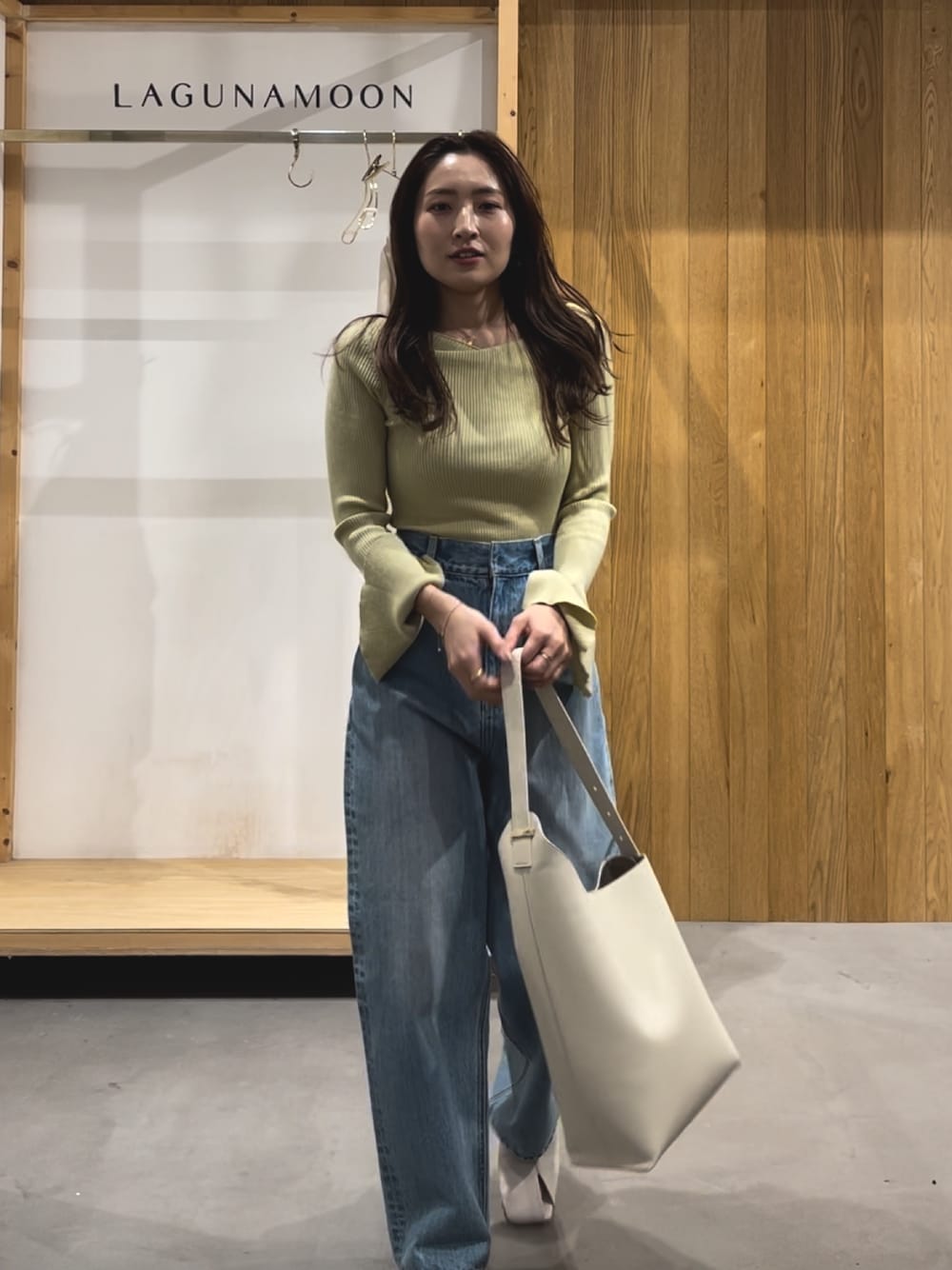 グリーン系のニット/セーター、ホワイト系のパンプス、ブルー系のデニムパンツを着用したレディースの冬コーディネートの1枚目の写真