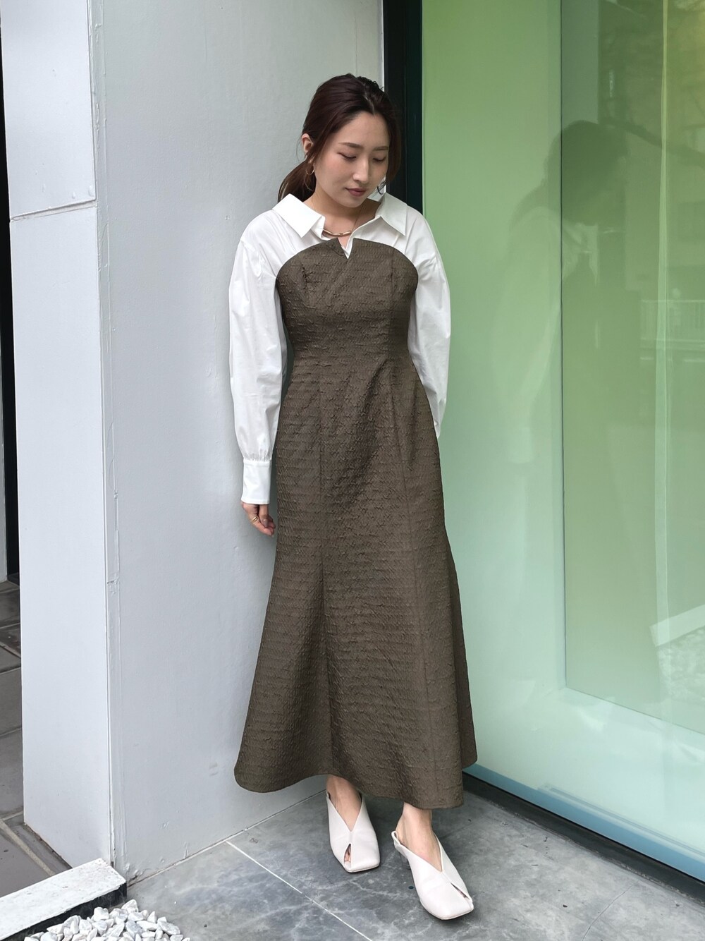 ホワイト系のパンプス、ブラウン系のワンピース、ゴールド系のネックレスを着用したレディースの春コーディネートの1枚目の写真