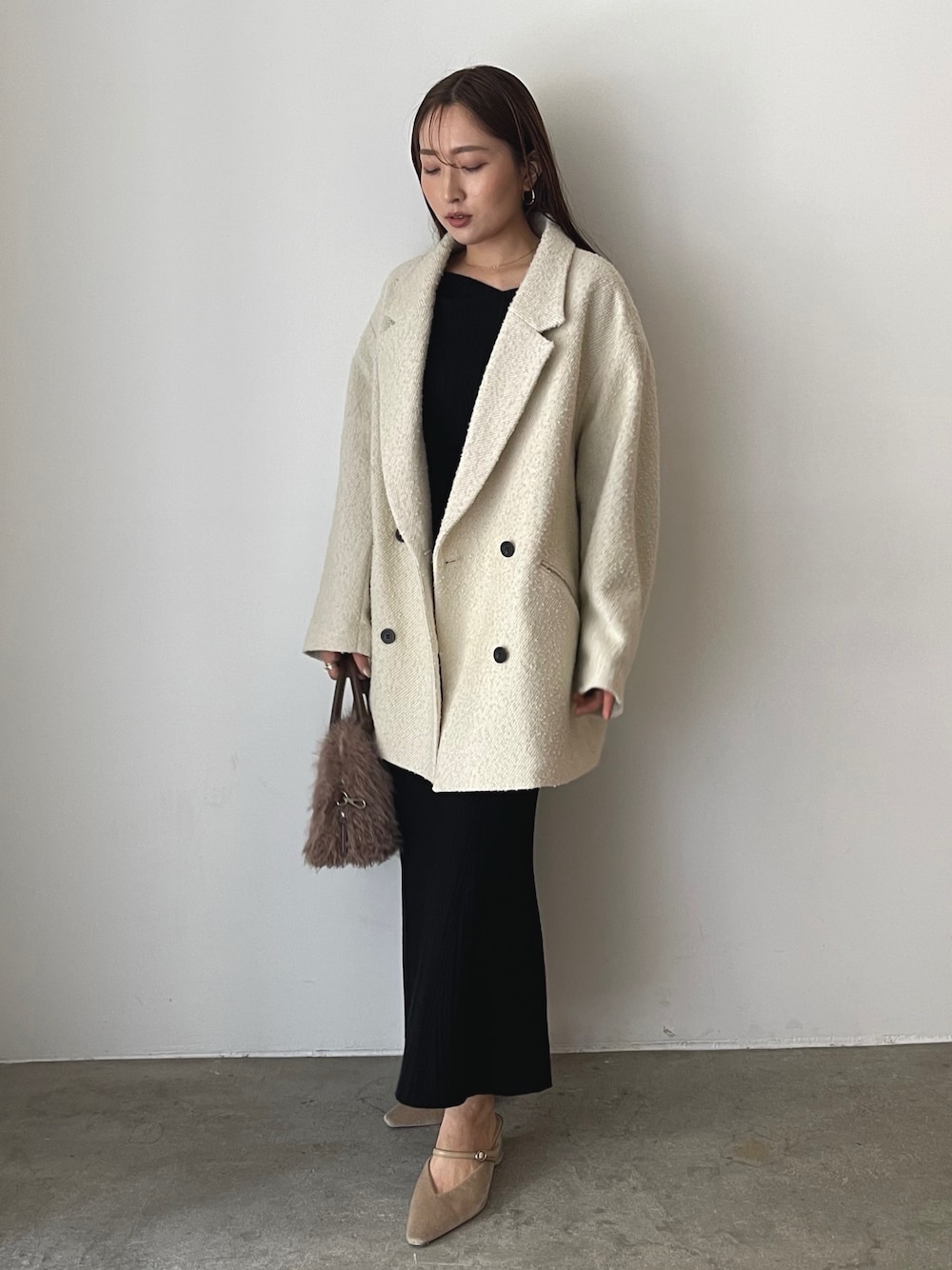 ブラック系のワンピース、ベージュ系のパンプス、ブラウン系のボストンバッグを着用したレディースの秋コーディネートの1枚目の写真