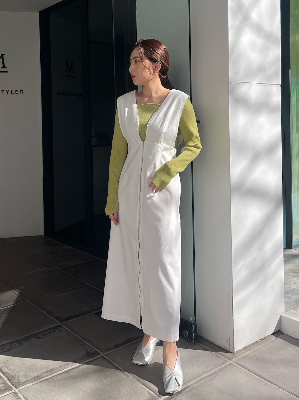 シルバー系のパンプス、グリーン系のニット/セーター、ホワイト系のジャンパースカートを着用したレディースの冬コーディネートの1枚目の写真