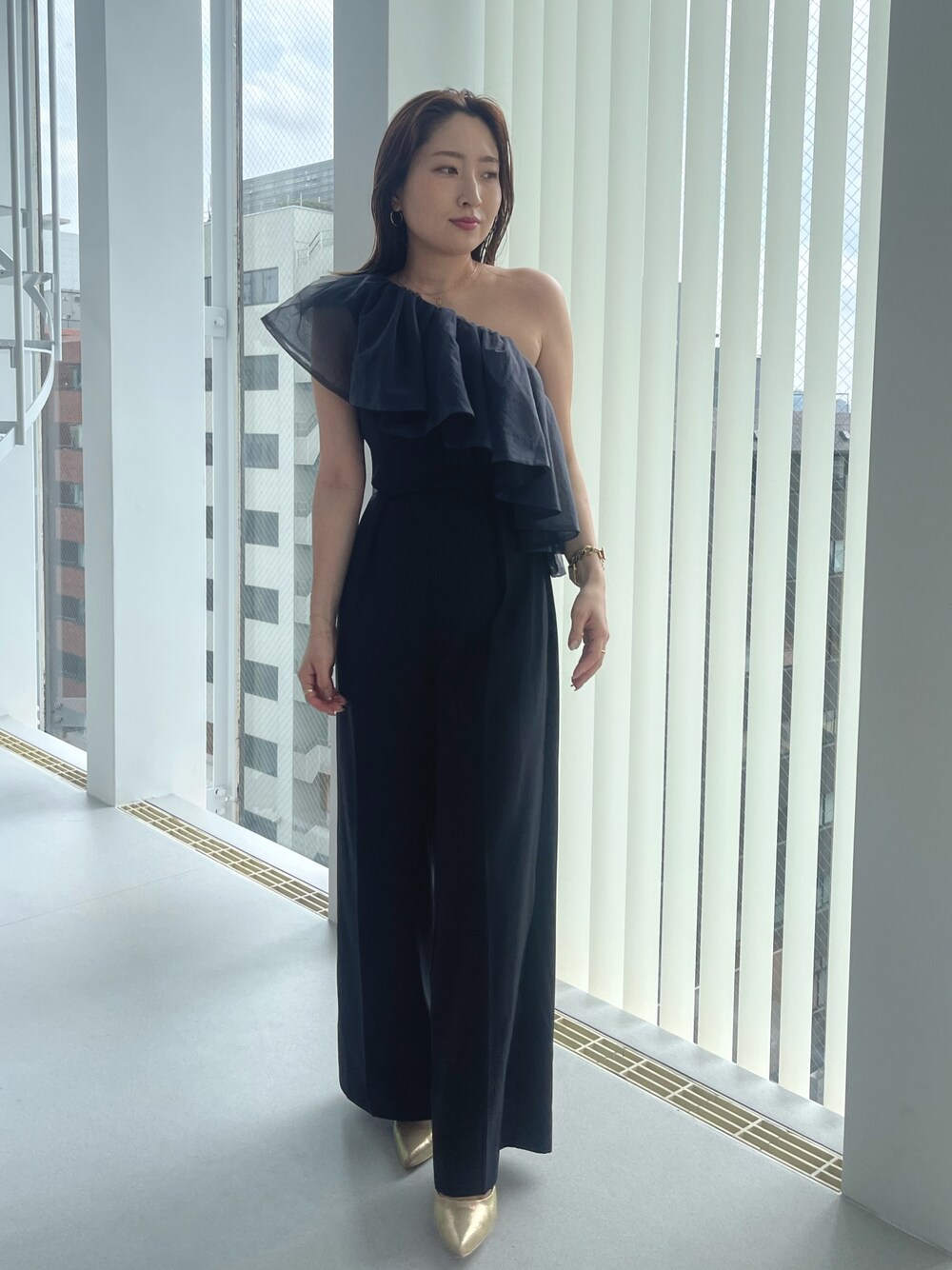 ゴールド系のパンプス、ブラック系のパンツドレスを着用したレディースの夏コーディネートの1枚目の写真