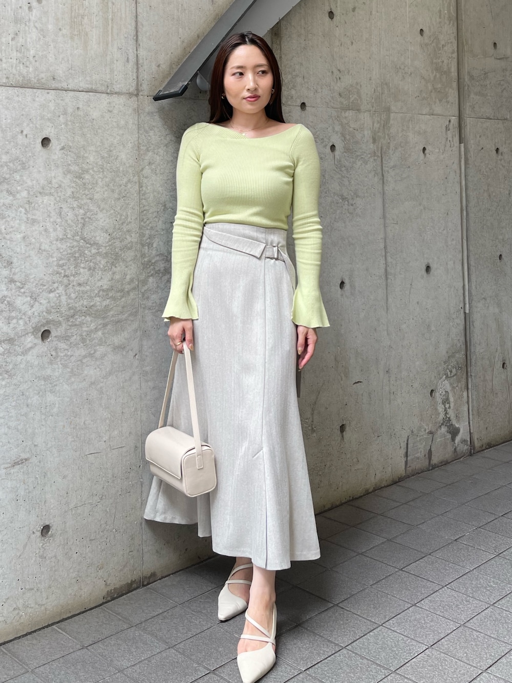 ホワイト系のショルダーバッグ、ホワイト系のパンプス、グレー系のスカートを着用したレディースの秋コーディネートの1枚目の写真