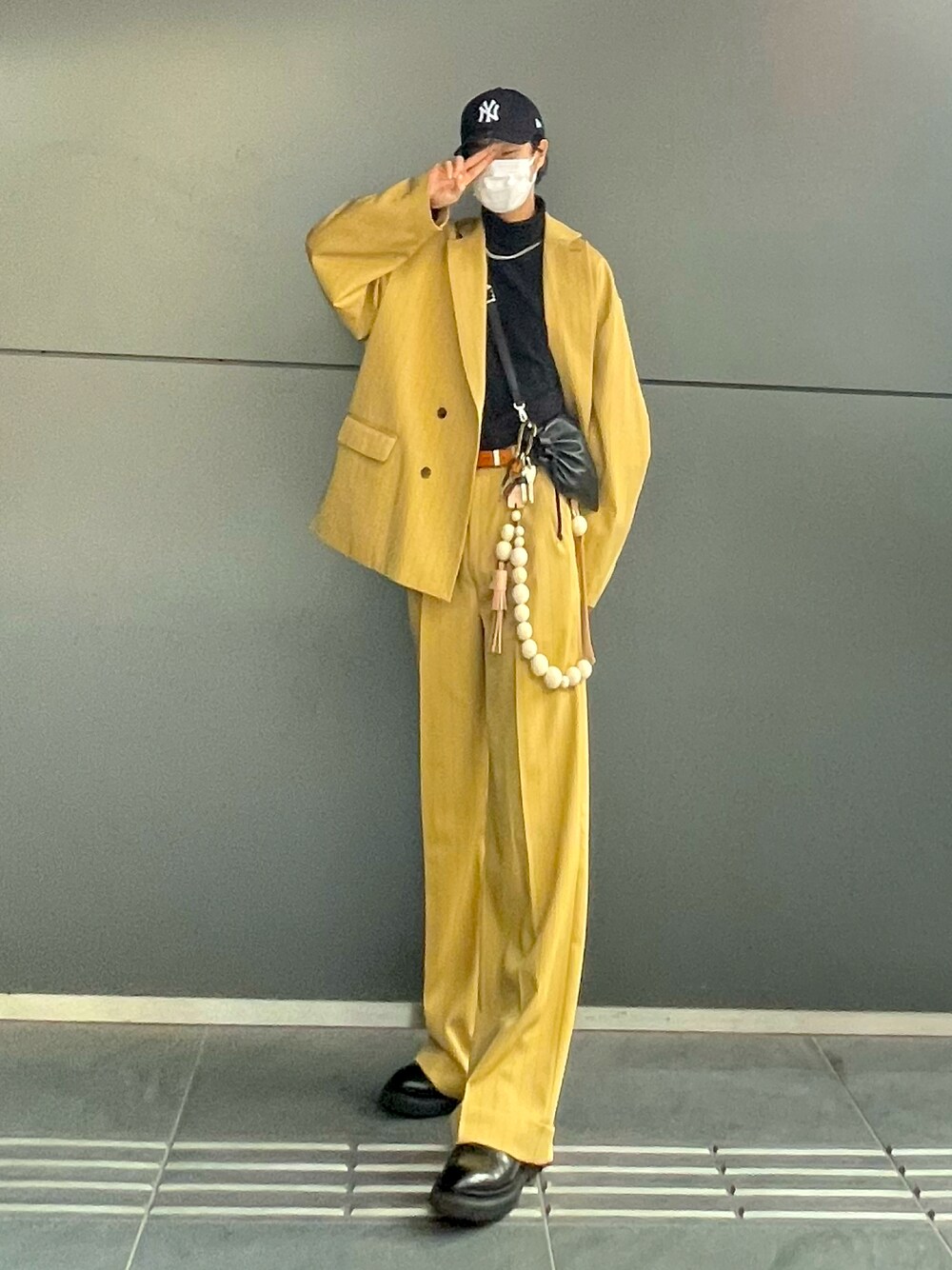 ブラック系のブーツ、イエロー系のスラックス、ブラック系のショルダーバッグを着用したメンズの秋コーディネートの1枚目の写真