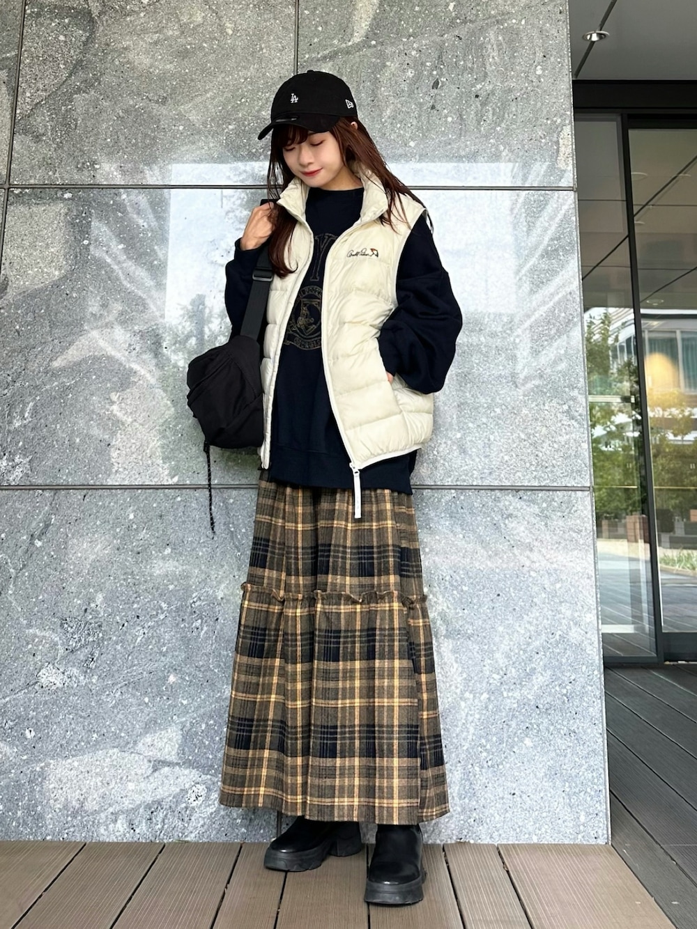 ブルー系のスウェット、ホワイト系のダウンベスト、イエロー系のスカートを着用したレディースの秋コーディネートの1枚目の写真