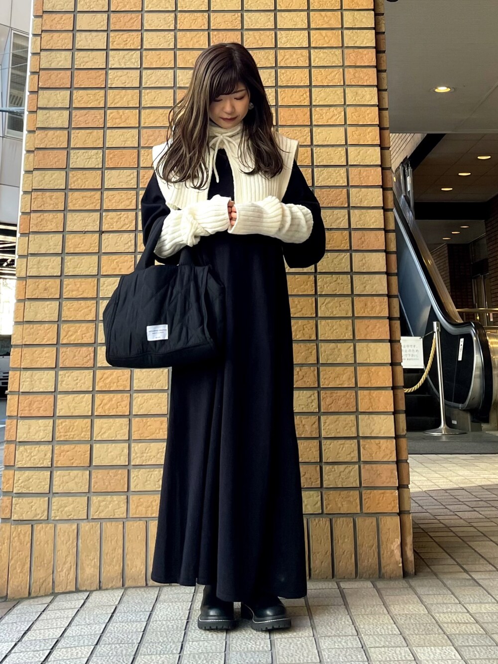 ブルー系のワンピース、ブラック系のトートバッグ、ブラック系のブーツを着用したレディースの冬コーディネートの1枚目の写真