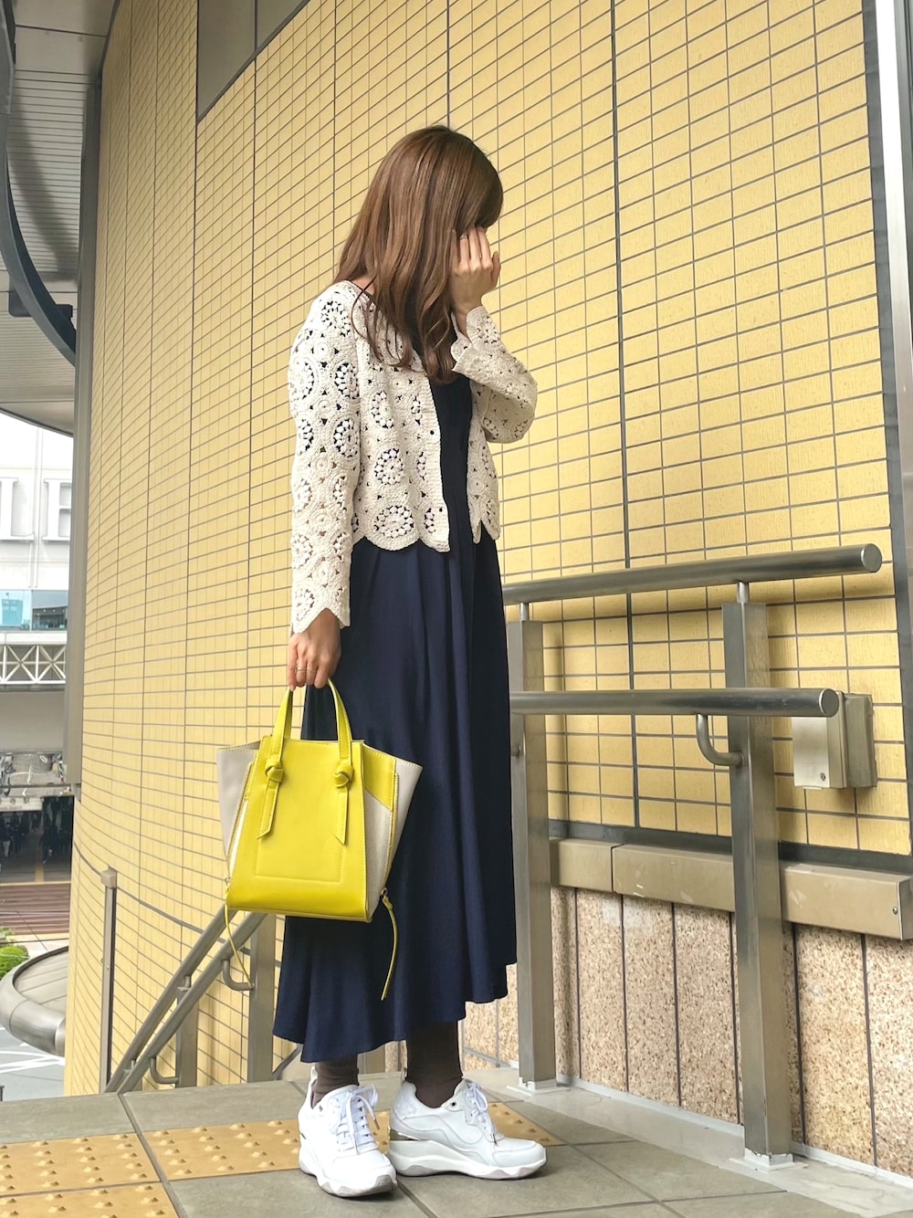 イエロー系のショルダーバッグ、ホワイト系のカーディガン/ボレロ、ブルー系のワンピースを着用したレディースの春コーディネートの1枚目の写真