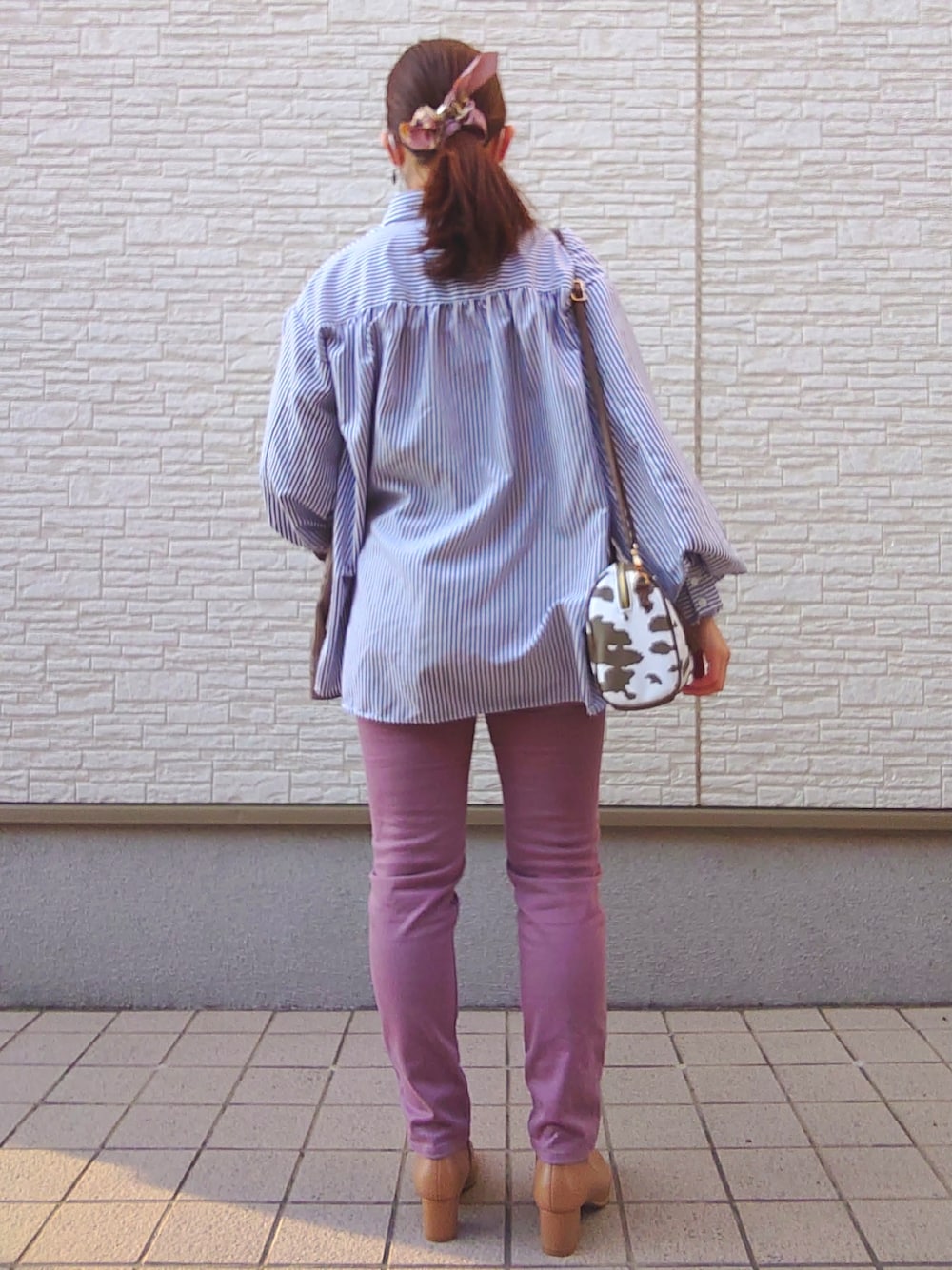 ピンク系のパンツ、イエロー系のブーツ、ブラウン系のノーカラージャケットを着用したレディースの春コーディネートの4枚目の写真