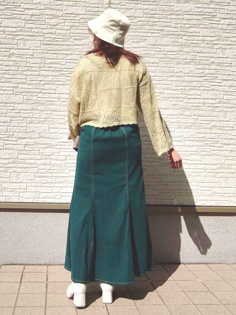 グリーン系のトップス、グリーン系のスカート、ブラウン系のノーカラージャケットを着用したレディースの春コーディネートの2枚目の写真