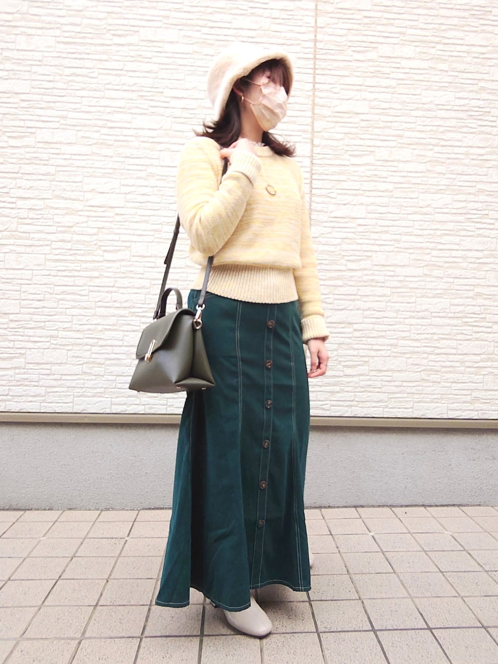 ホワイト系のジャケット/アウター、イエロー系のニット/セーター、グリーン系のスカートを着用したレディースの冬コーディネートの2枚目の写真