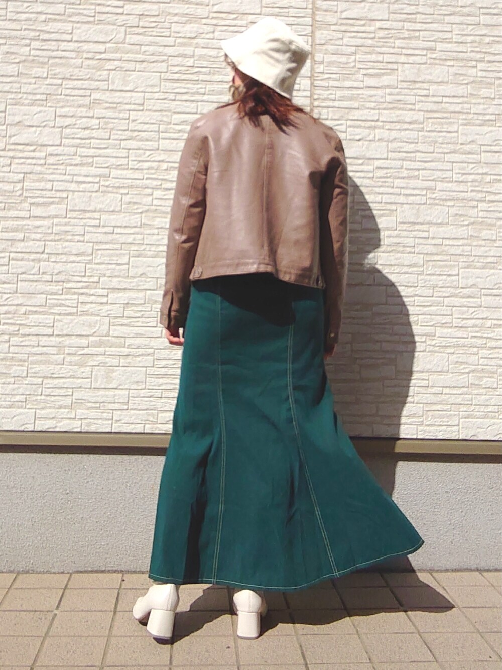 グリーン系のトップス、グリーン系のスカート、ブラウン系のノーカラージャケットを着用したレディースの春コーディネートの5枚目の写真