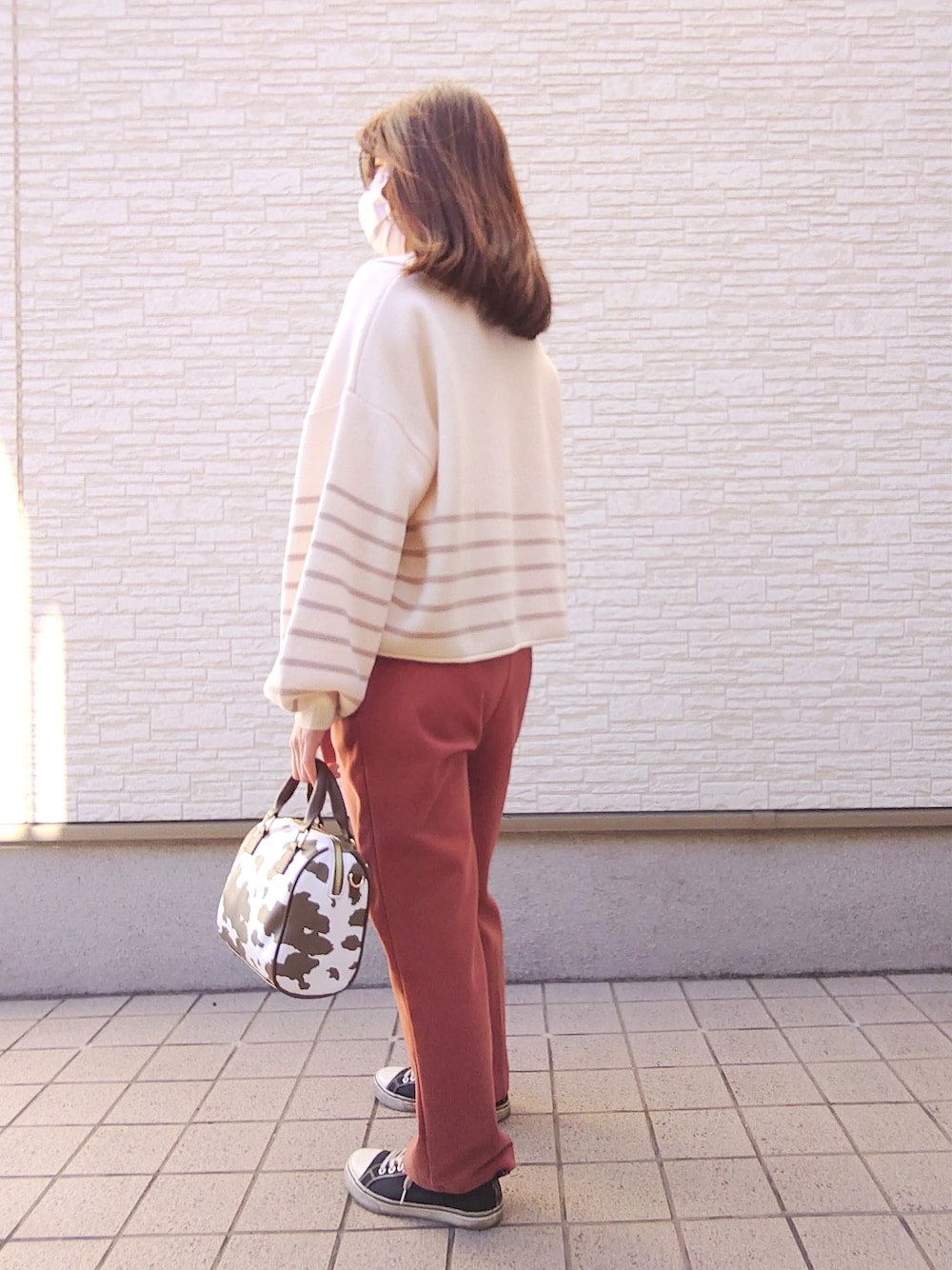 ベージュ系のトップス、オレンジ系のパンツ、その他のボストンバッグを着用したレディースの冬コーディネートの2枚目の写真