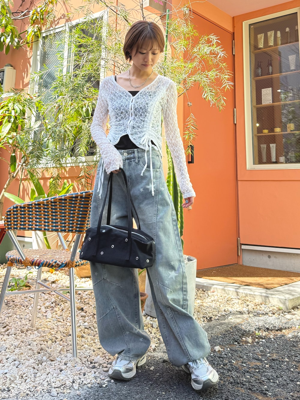ホワイト系のカーディガン/ボレロ、ブルー系のデニムパンツ、ブラック系のショルダーバッグを着用したレディースの春コーディネートの1枚目の写真