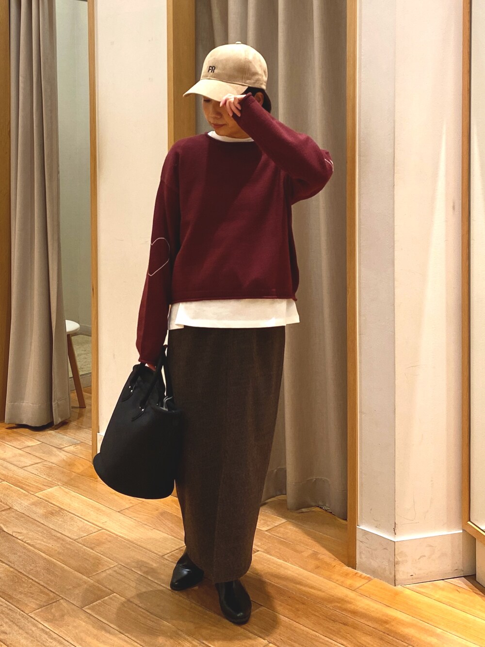 レッド系のニット/セーター、ブラウン系のスカート、ホワイト系のTシャツ/カットソーを着用したレディースの秋コーディネートの1枚目の写真