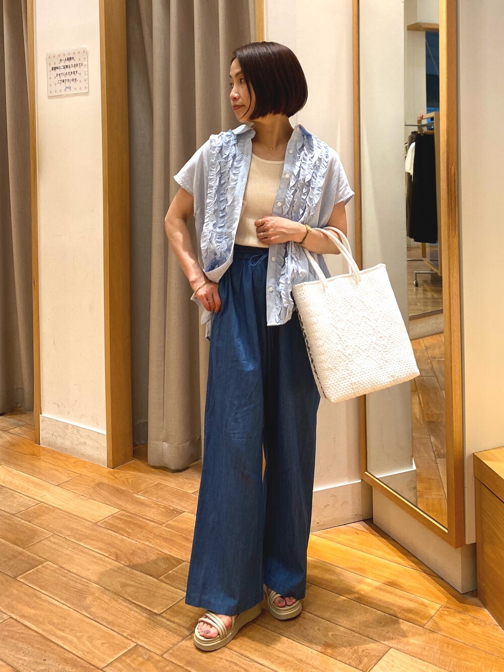 ブルー系のデニムパンツ、ホワイト系のかごバッグ、ブルー系のシャツ/ブラウスを着用したレディースの夏コーディネートの1枚目の写真