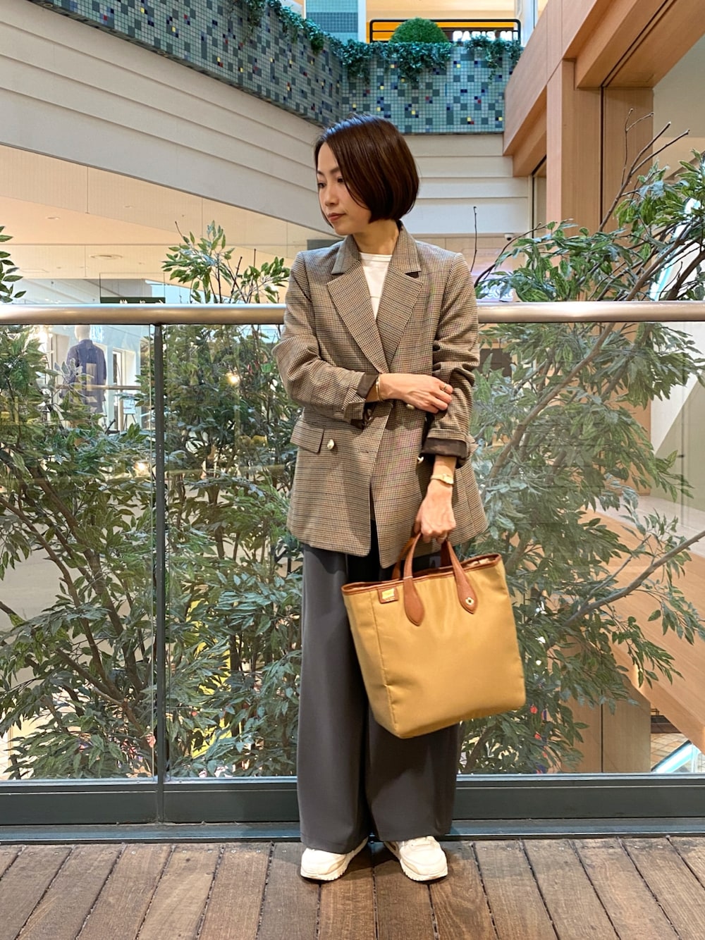 ベージュ系のテーラードジャケット、ホワイト系のベスト、イエロー系のショルダーバッグを着用したレディースの秋コーディネートの1枚目の写真