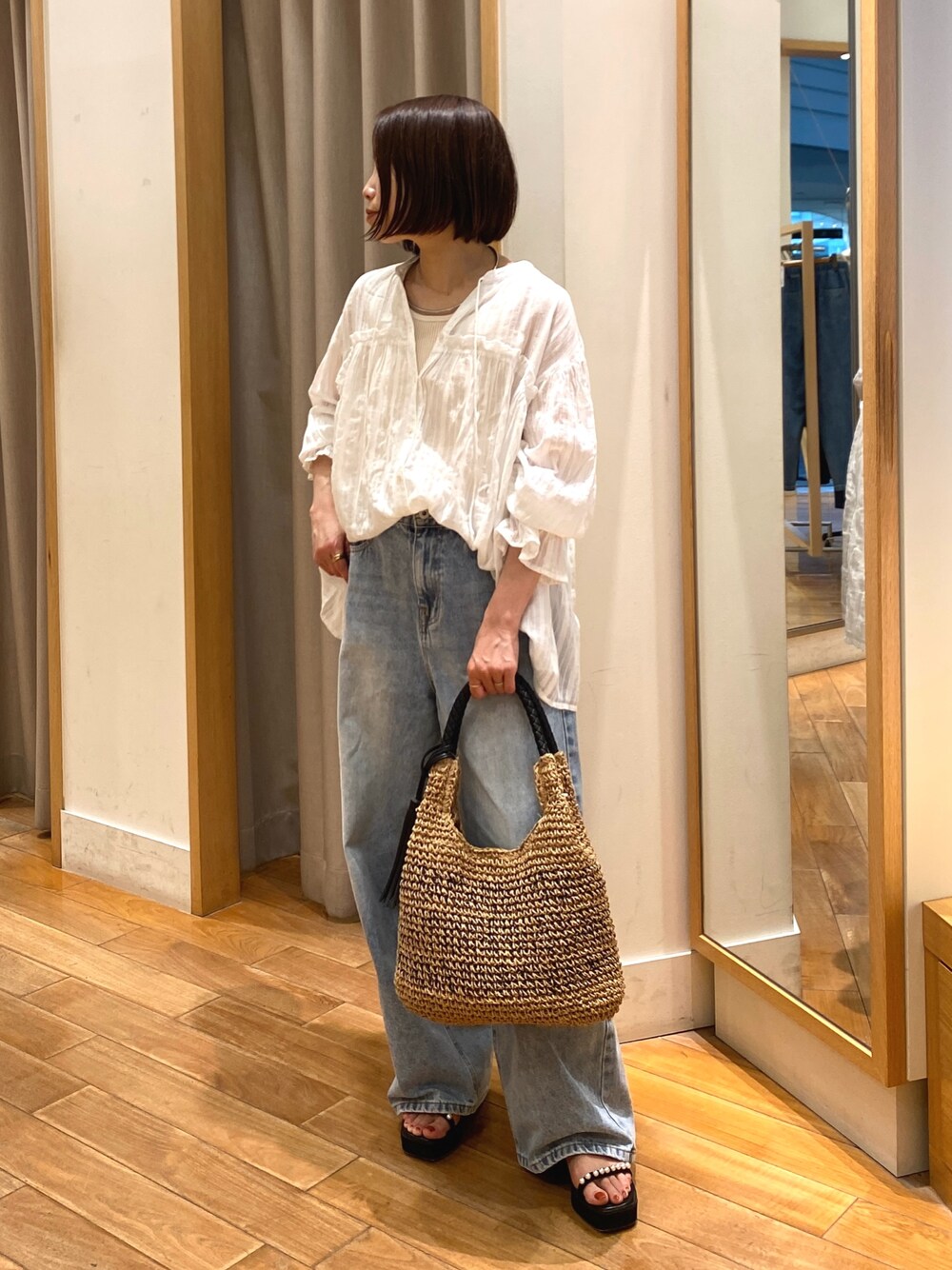 ホワイト系のシャツ/ブラウス、ブラウン系のかごバッグ、ブルー系のデニムパンツを着用したレディースの夏コーディネートの1枚目の写真