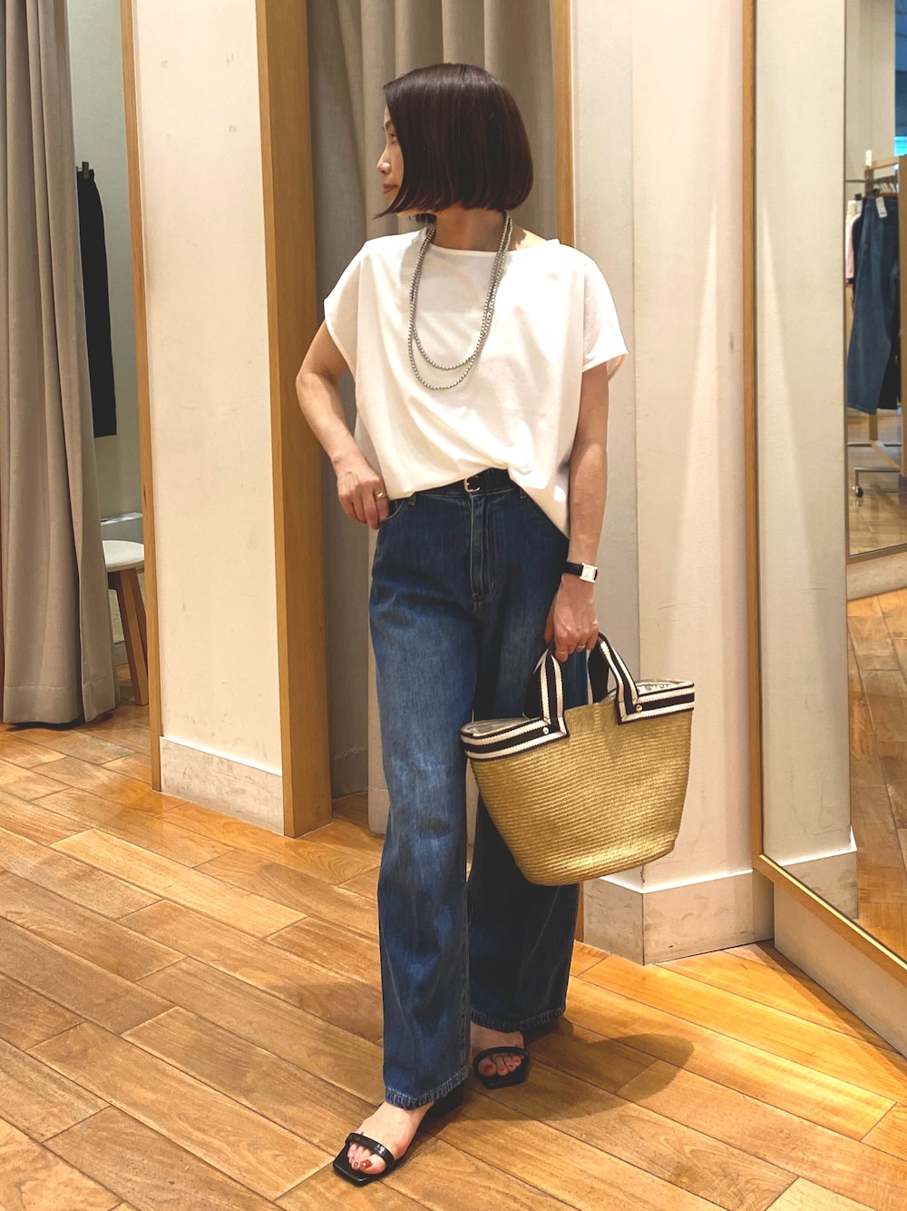 ブルー系のデニムパンツ、ホワイト系のTシャツ/カットソー、ベージュ系のかごバッグを着用したレディースの夏コーディネートの1枚目の写真