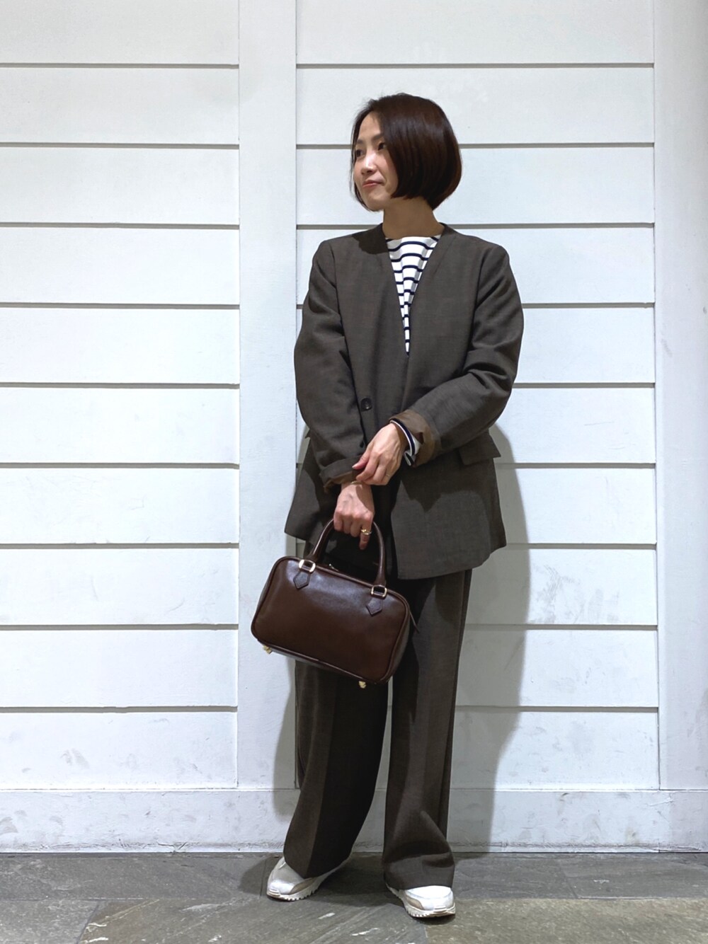 ブラウン系のハンドバッグ、ホワイト系のTシャツ/カットソー、ブラウン系のノーカラージャケットを着用したレディースの秋コーディネートの1枚目の写真