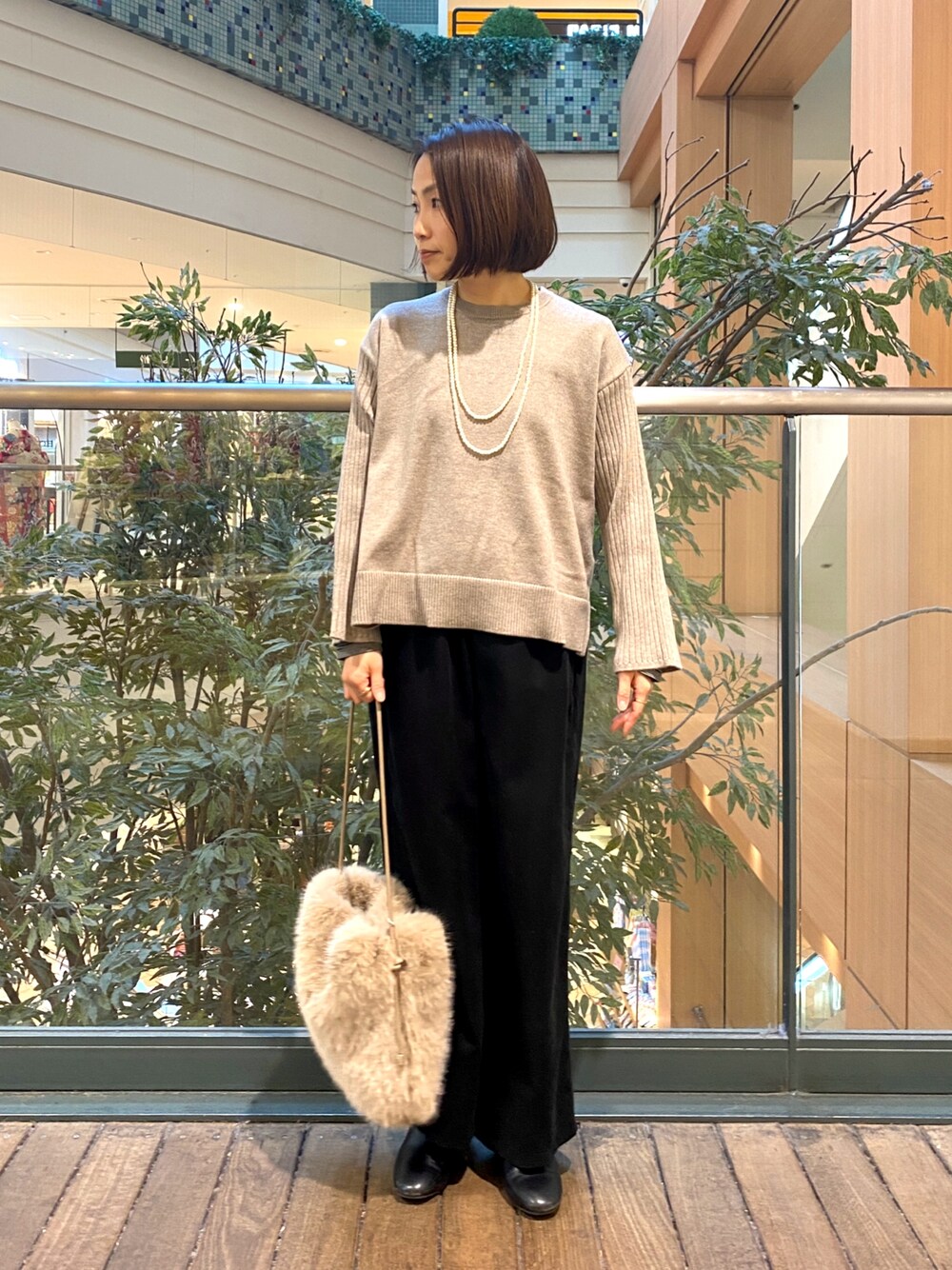 ブラック系のその他パンツ、ベージュ系のハンドバッグ、ベージュ系のニット/セーターを着用したレディースの冬コーディネートの1枚目の写真