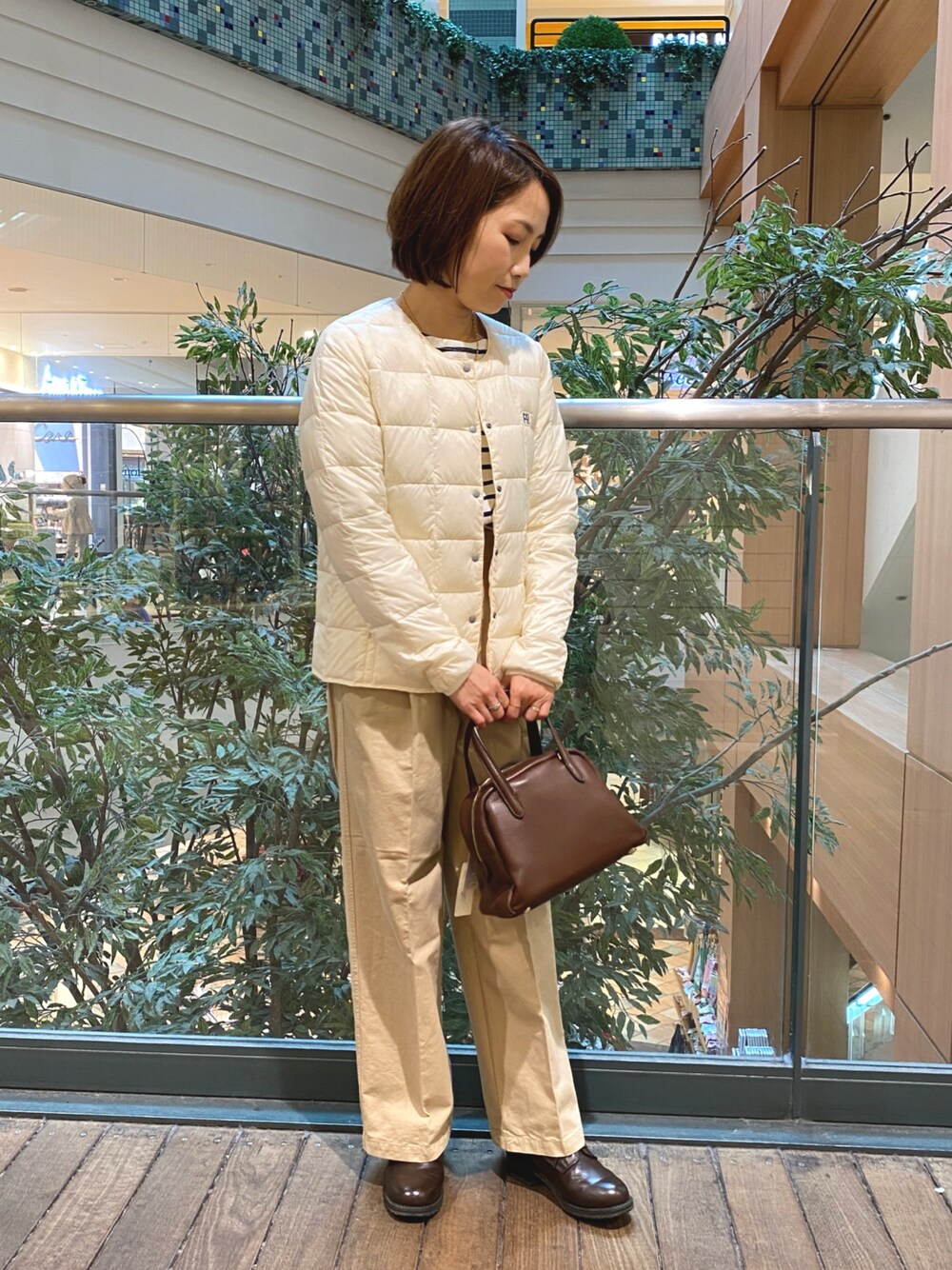 ホワイト系のダウンジャケット/コート、ホワイト系のTシャツ/カットソー、ブラウン系のボストンバッグを着用したレディースの秋コーディネートの1枚目の写真