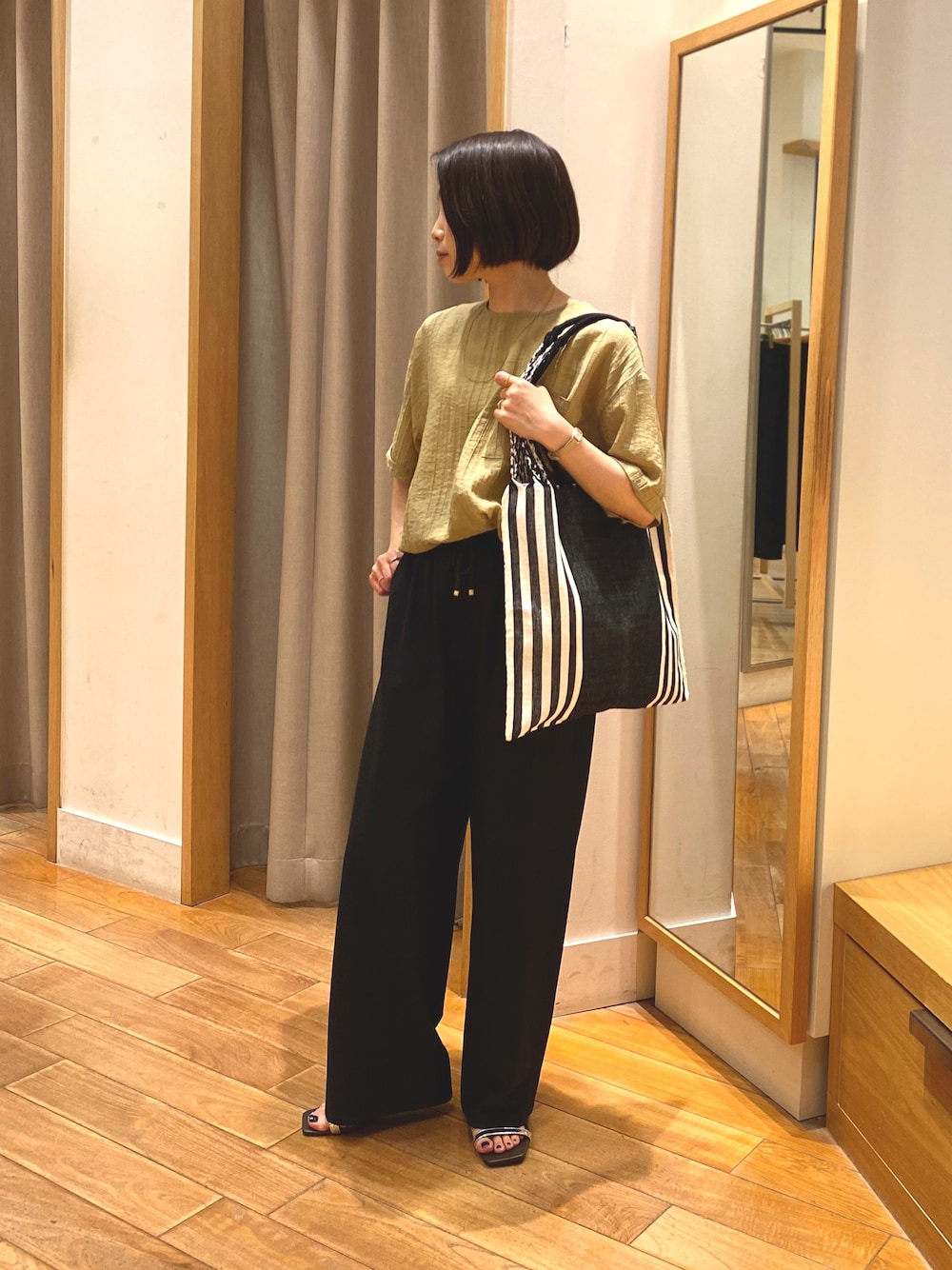 イエロー系のシャツ/ブラウス、グレー系のその他パンツ、ゴールド系のネックレスを着用したレディースの春コーディネートの1枚目の写真