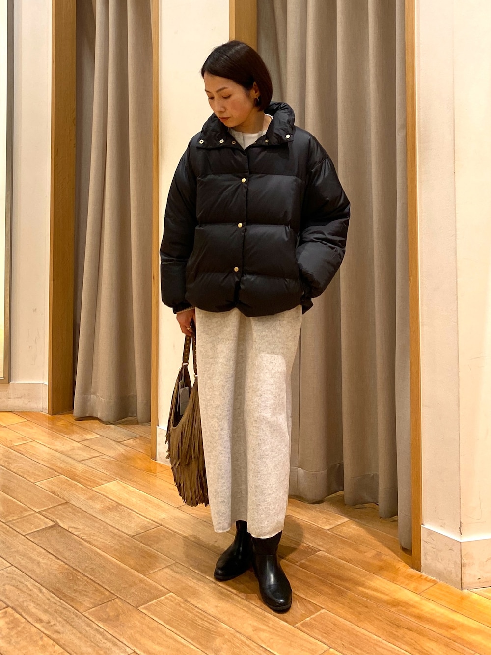 ベージュ系のショルダーバッグ、ブラック系のダウンジャケット/コート、ホワイト系のTシャツ/カットソーを着用したレディースの秋コーディネートの1枚目の写真