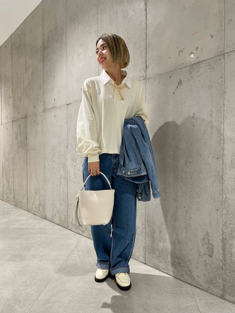 ベージュ系のショルダーバッグ、ホワイト系のローファー、ベージュ系のポロシャツを着用したレディースの夏コーディネートの1枚目の写真