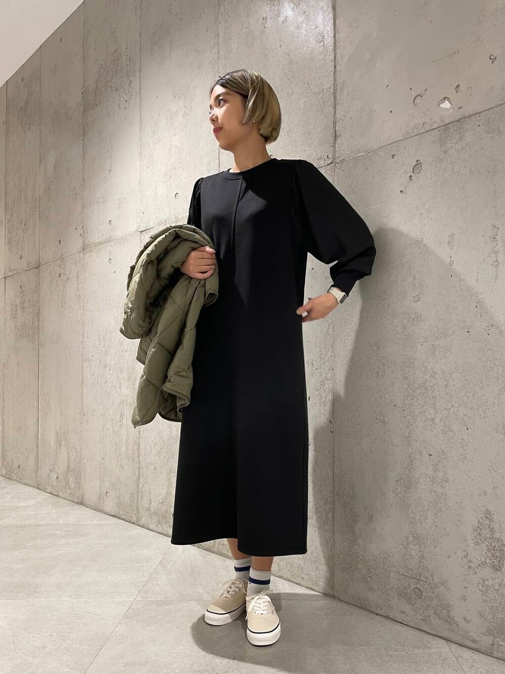 ホワイト系のスニーカー、グリーン系のダウンジャケット/コート、ブラック系のワンピースを着用したレディースの秋コーディネートの1枚目の写真