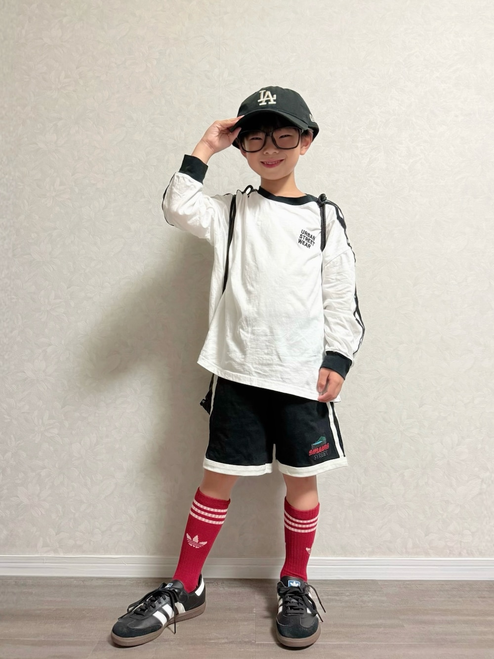 ブラック系のセットアップ、ホワイト系のTシャツ/カットソー、ブラック系のキャップを着用したキッズの秋コーディネートの1枚目の写真