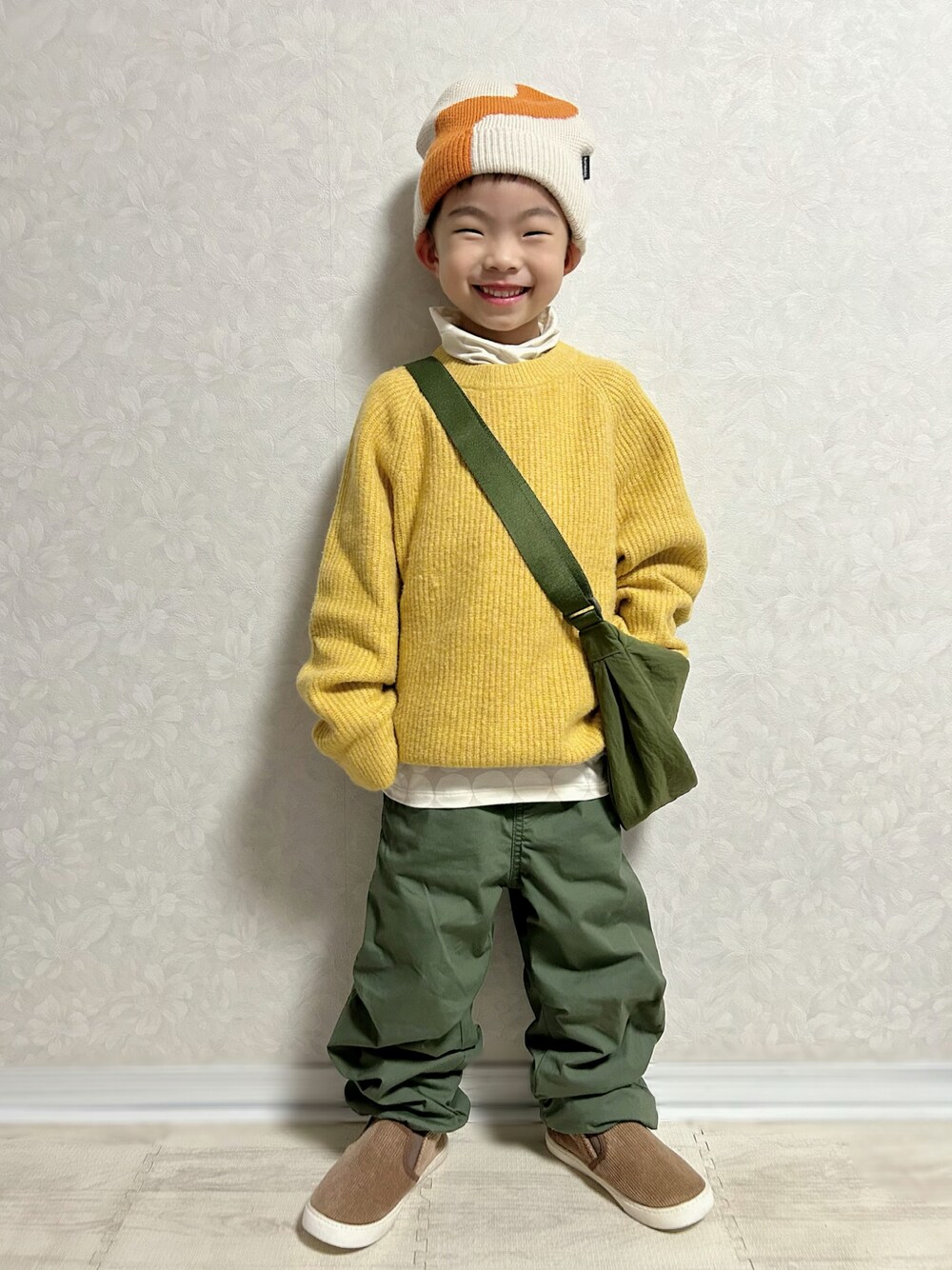 グレー系のTシャツ/カットソー、イエロー系のニット/セーター、グリーン系のショルダーバッグを着用したキッズの冬コーディネートの1枚目の写真