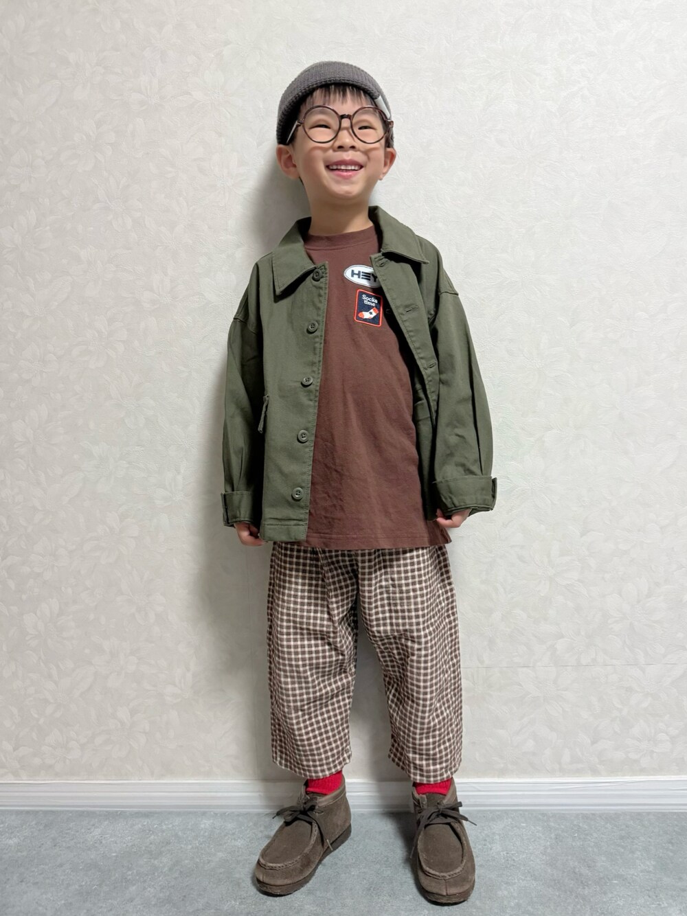 ブラウン系のTシャツ/カットソー、グリーン系のジャケット/アウター、ブラウン系のパンツを着用したキッズの秋コーディネートの1枚目の写真